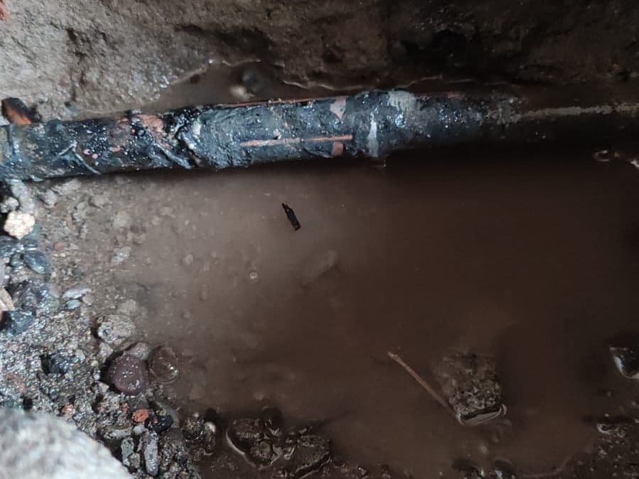 Excavación que expone una cañería antigua con filtración en Ñuñoa